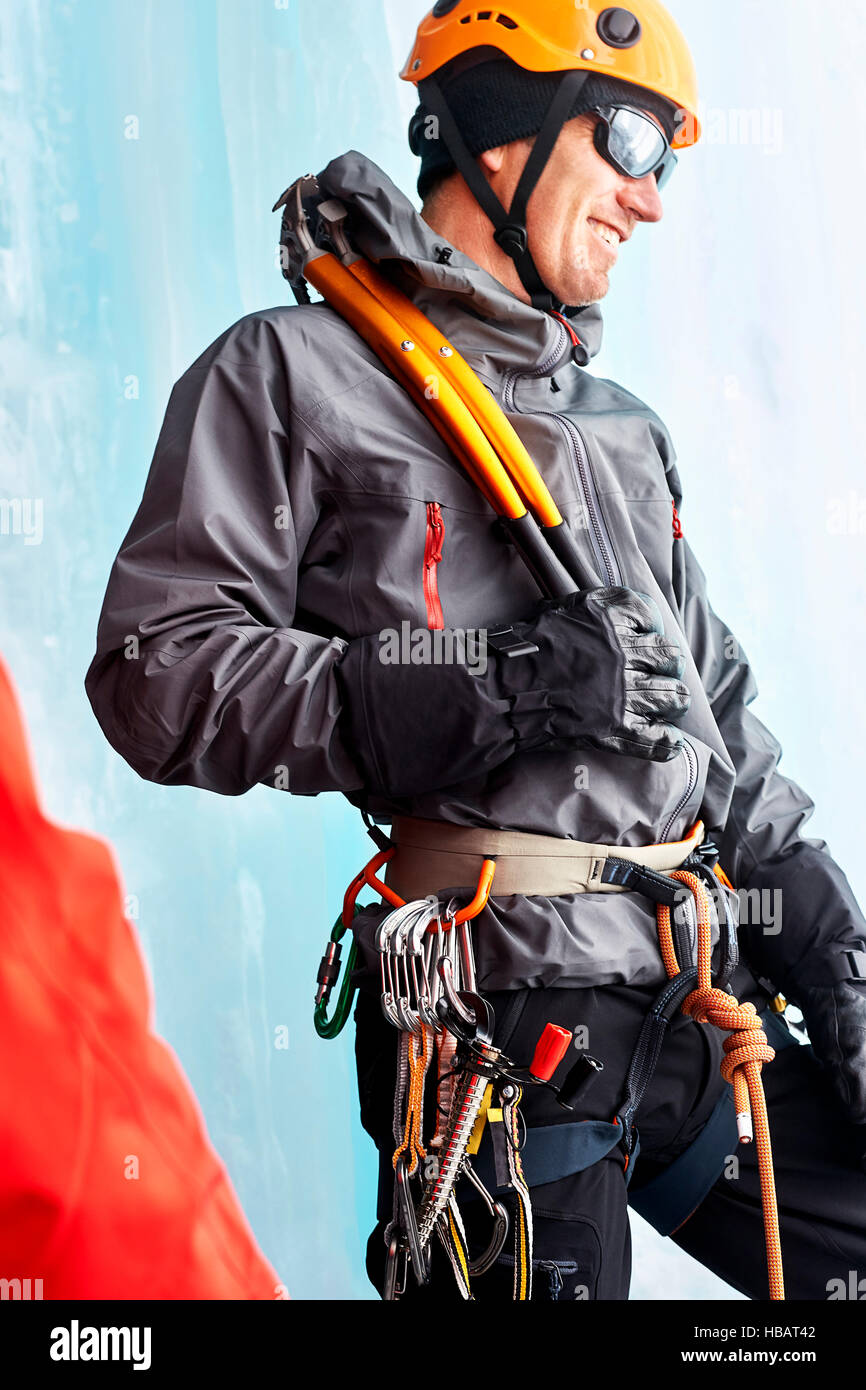 Ice Climber con arrampicata attrezzature che guarda lontano sorridente Foto Stock