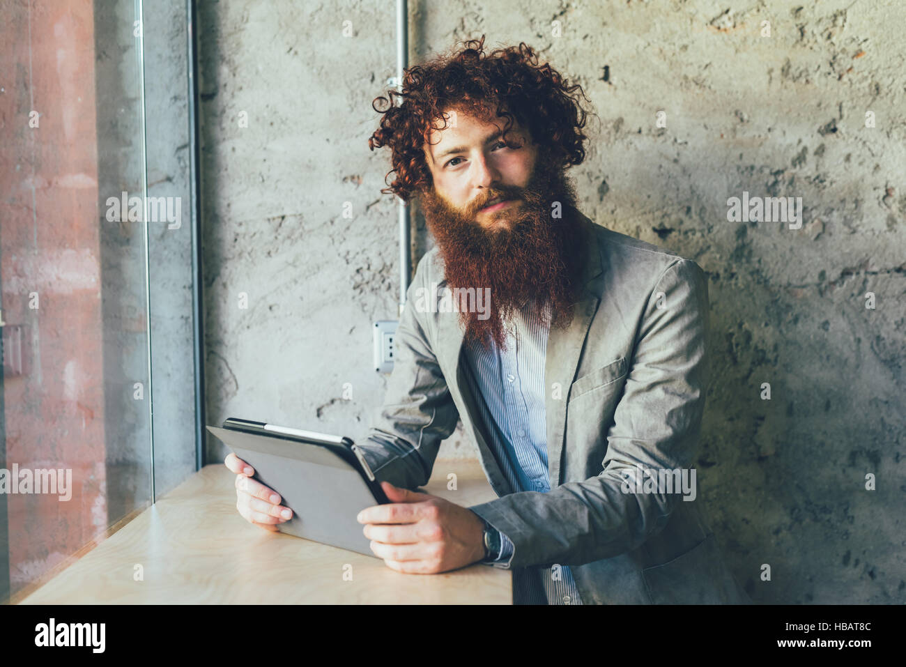 Ritratto di giovane maschio hipster con ricci capelli rossi e la barba in ufficio Foto Stock