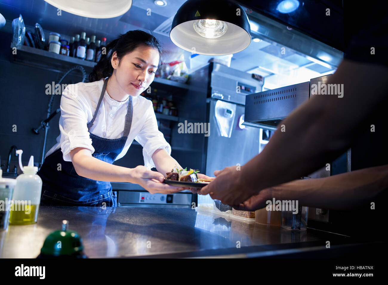 Lo Chef consegna pasti preparati al cameriere Foto Stock