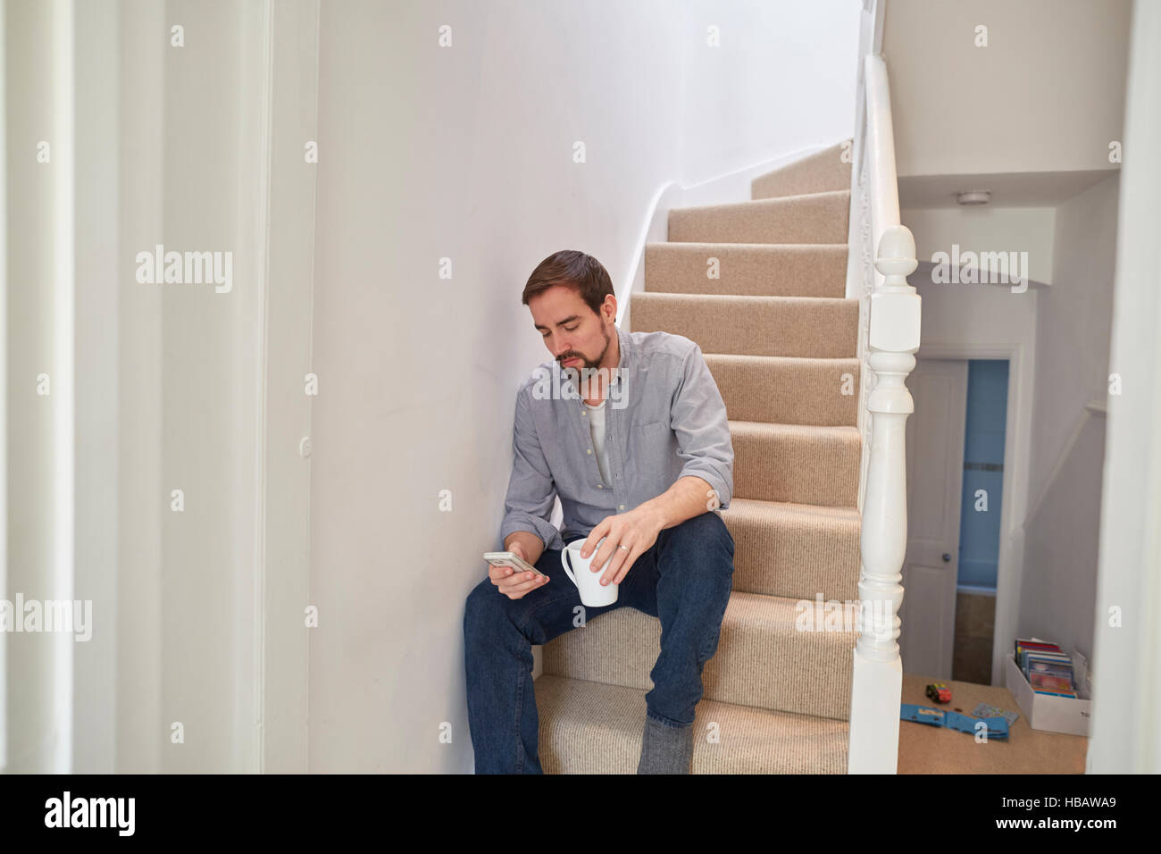 Metà uomo adulto seduto sulla scala di lettura di testi dello smartphone Foto Stock