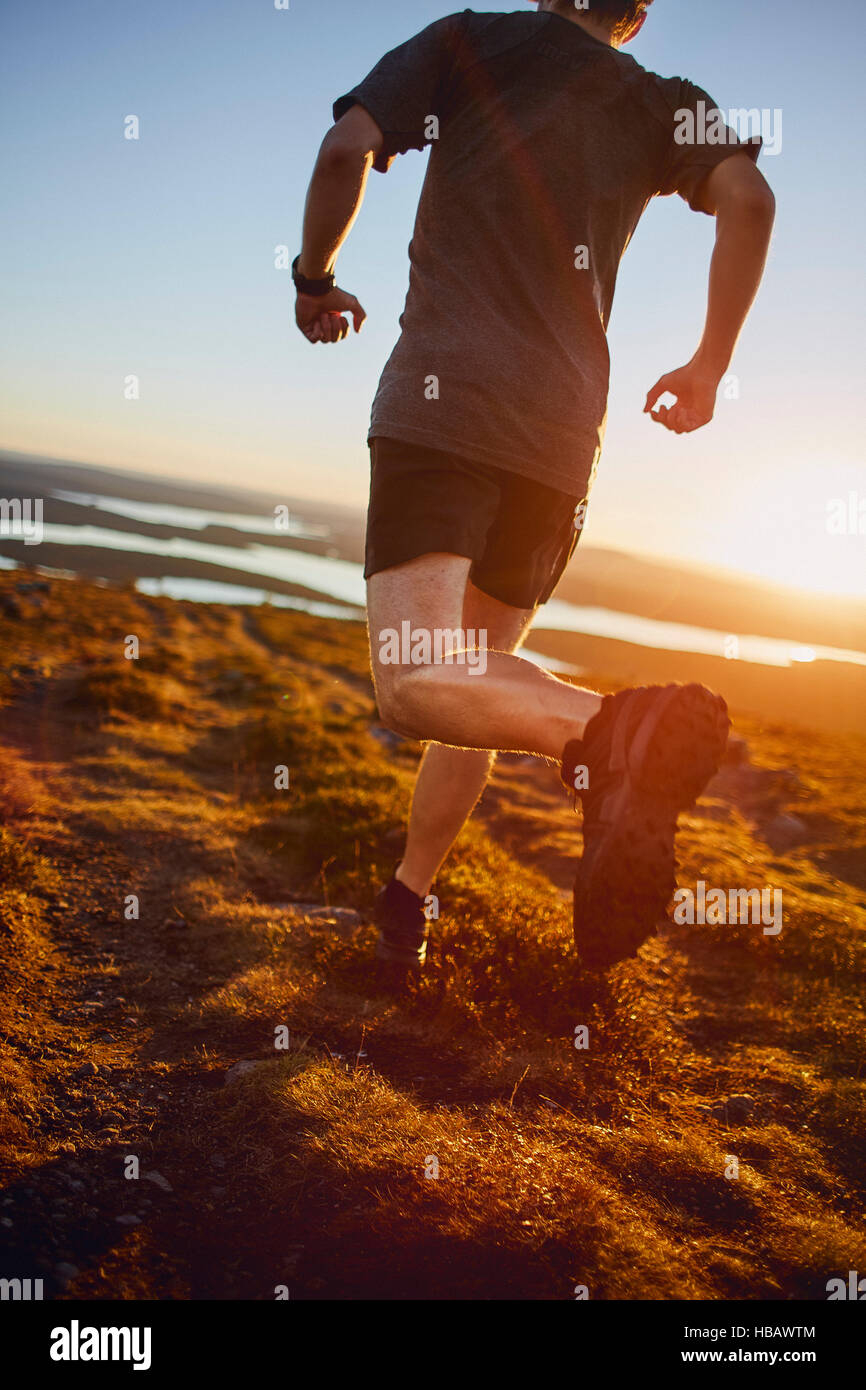 Uomo che corre sulla Scogliera al tramonto, Keimiotunturi, Lapponia, Finlandia Foto Stock