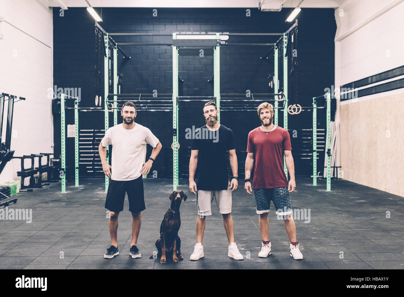 Ritratto di tre maschio cross trainer e cane in palestra Foto Stock