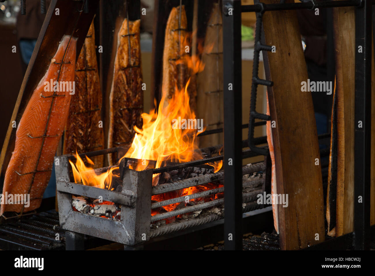 Una fotografia di alcuni salmone essendo cotta su fiamme aperte al mercatino di Natale a Basilea in Svizzera. Foto Stock