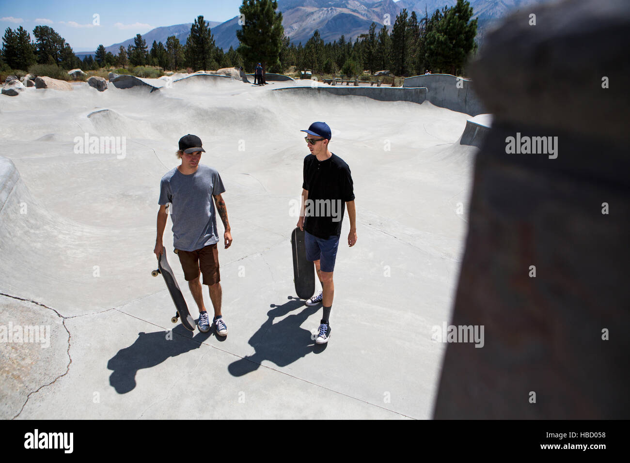 Due giovani skateboarders maschio chiacchierando in skate park, Mammoth Lakes, CALIFORNIA, STATI UNITI D'AMERICA Foto Stock