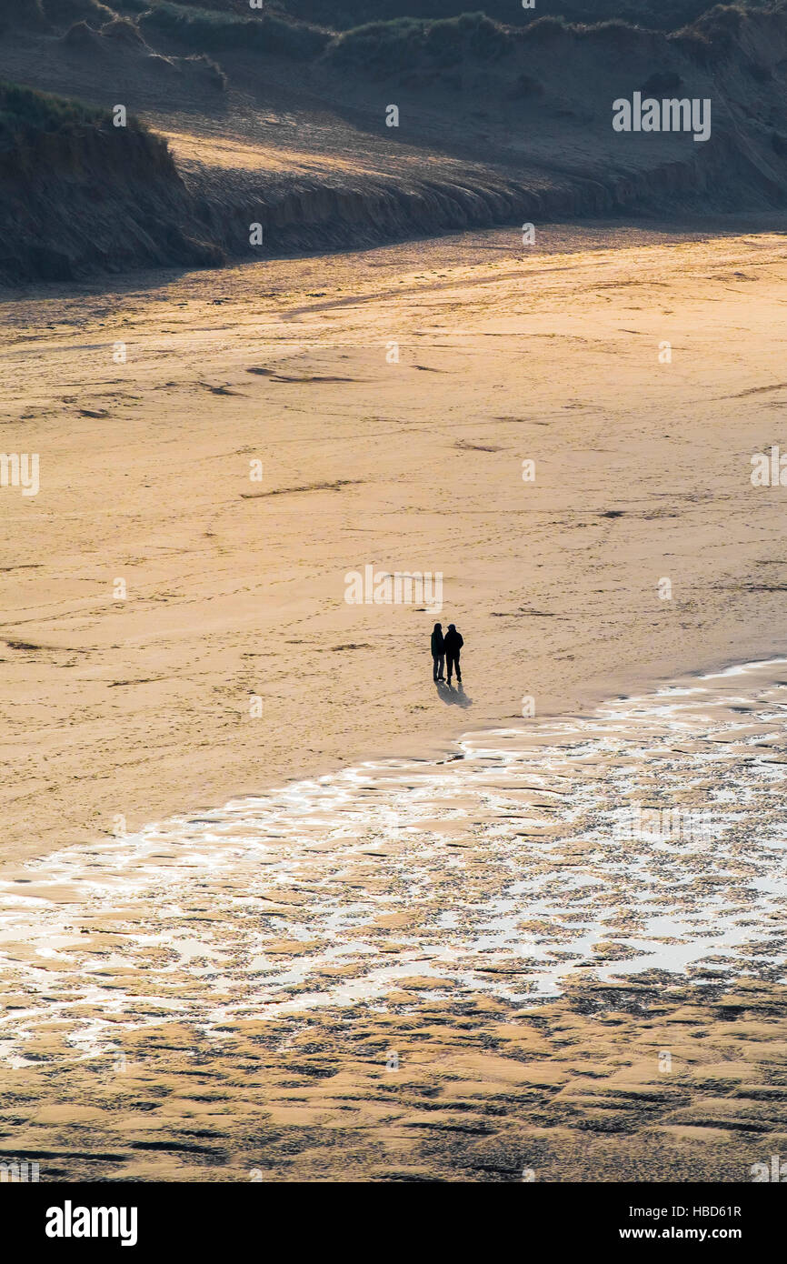 Due persone visto in silhouette e da una distanza su Crantock Beach in Newquay, Cornwall. Foto Stock