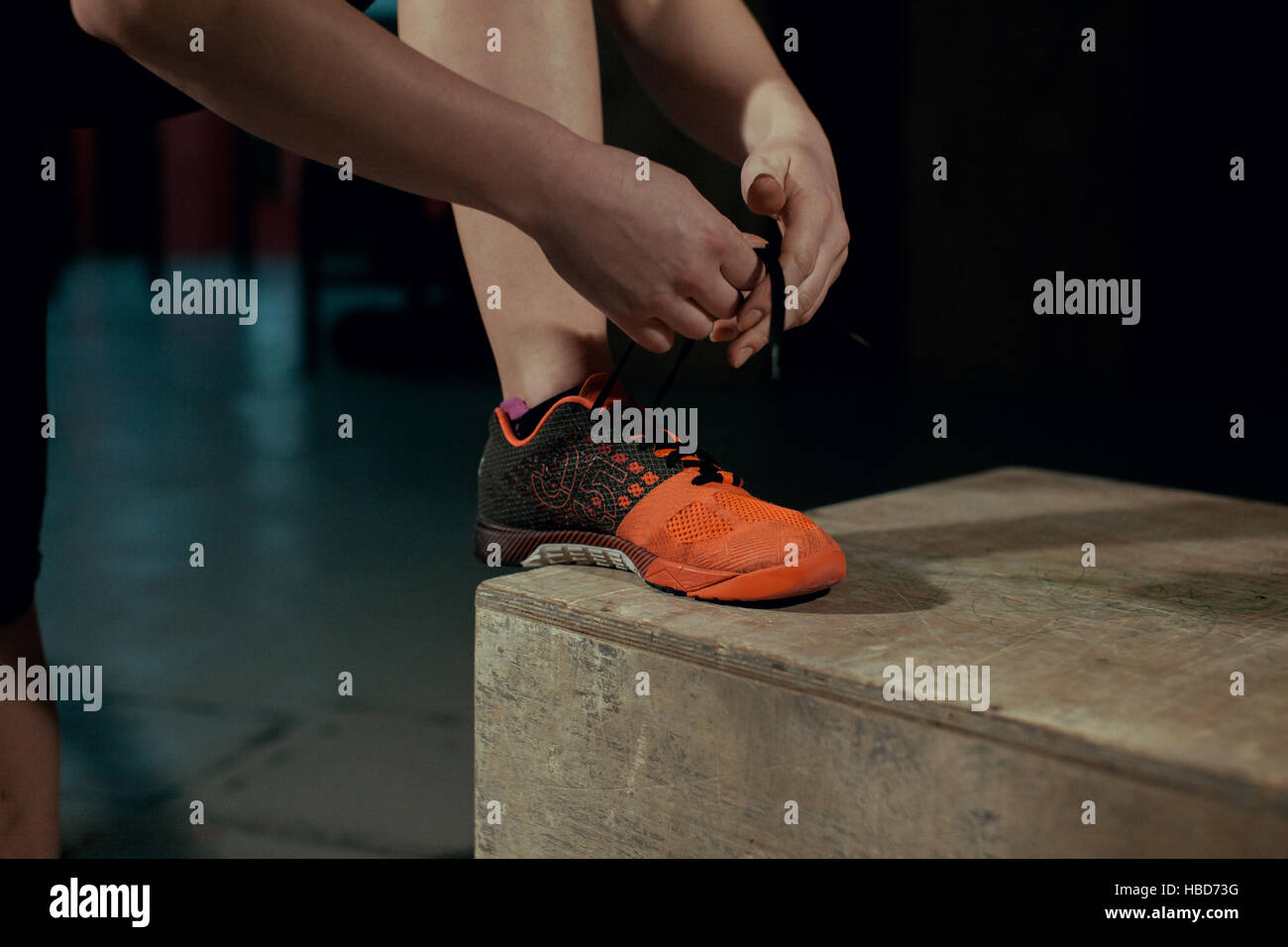 Ragazza giovane assicura i lacci sul sneakers in palestra. Foto Stock