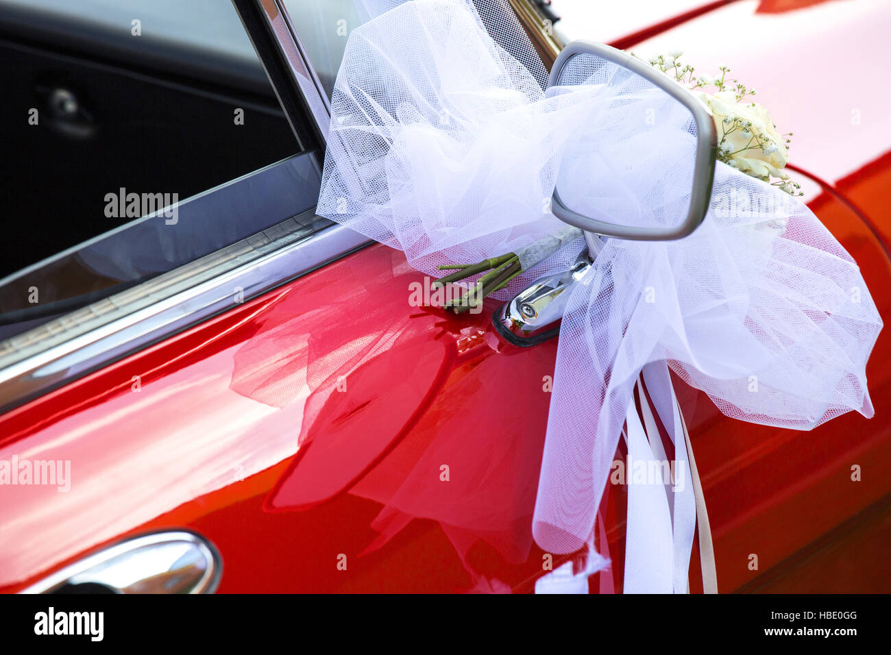 Piccolo fiore bouquet con prua bianco su una automobile rossa. Foto Stock