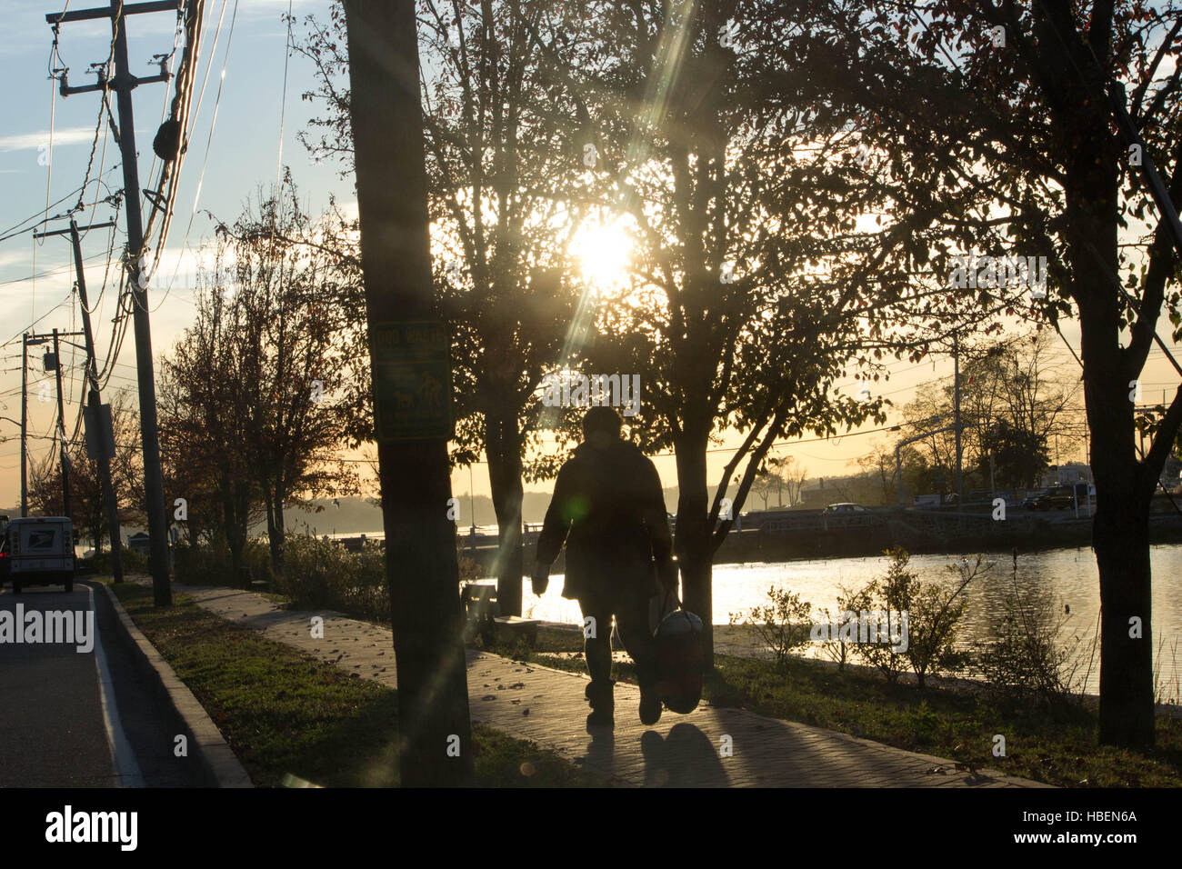 Tornando a casa- un residente locale pedonale off a piedi verso il tramonto come ella capi home su un ritardo di caduta stagione pomeriggio Foto Stock
