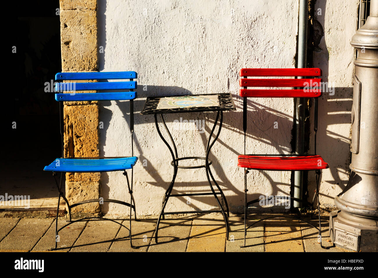 Sedie rosse e blu sul marciapiede con un piccolo tavolo, Limassol, Cipro. Foto Stock