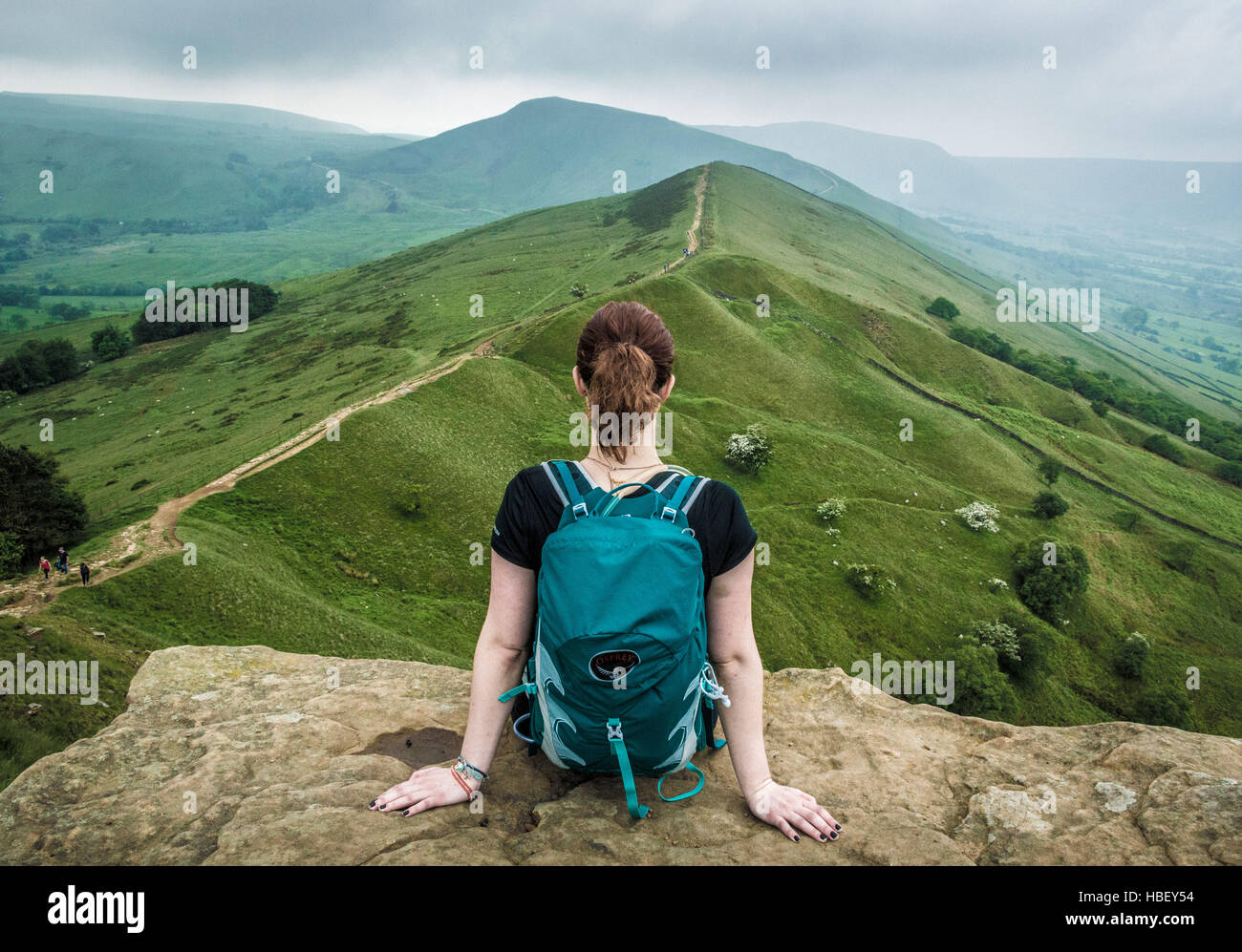 Donna seduta sul promontorio roccioso, Peak District, Derbyshire, Regno Unito. Foto Stock