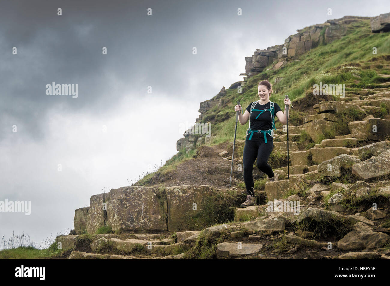 Femmina su una collina rocciosa percorso, Peak District, Derbyshire, Regno Unito. Foto Stock