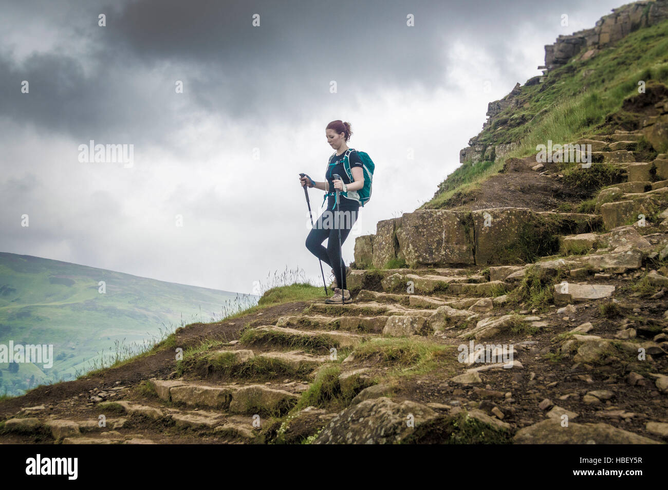 Femmina su una collina rocciosa percorso, Peak District, Derbyshire, Regno Unito. Foto Stock