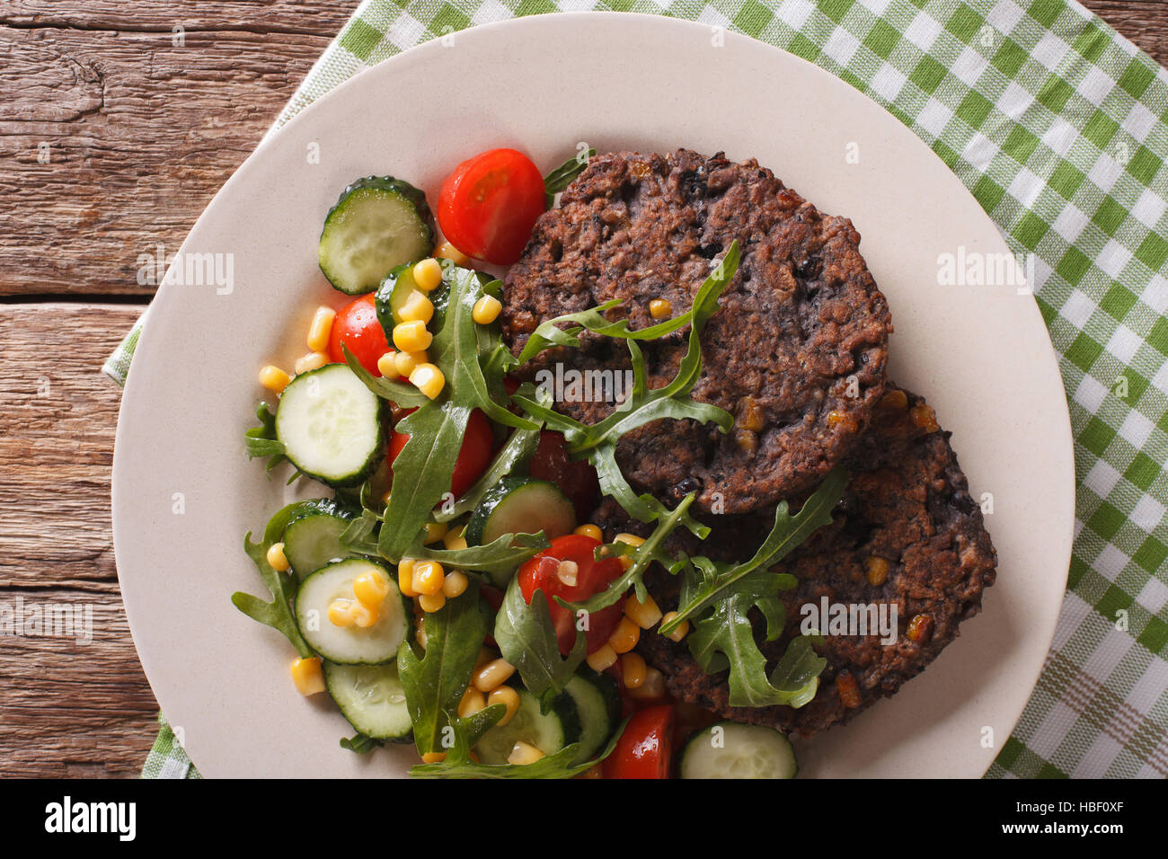Cibo vegetariano: chicco nero hamburger e insalata di verdure fresche di close-up su una piastra orizzontale di vista da sopra Foto Stock
