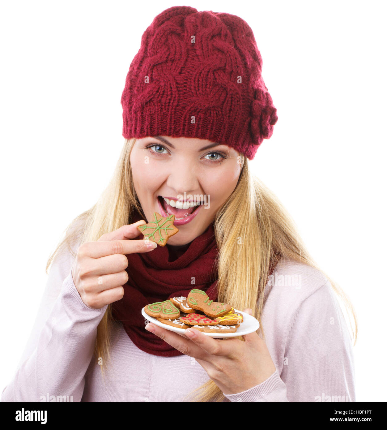 Sorridenti donna che indossa cappello di lana e scialle e azienda gingerbreads o cookie di festosa, tempo di Natale, sfondo bianco Foto Stock