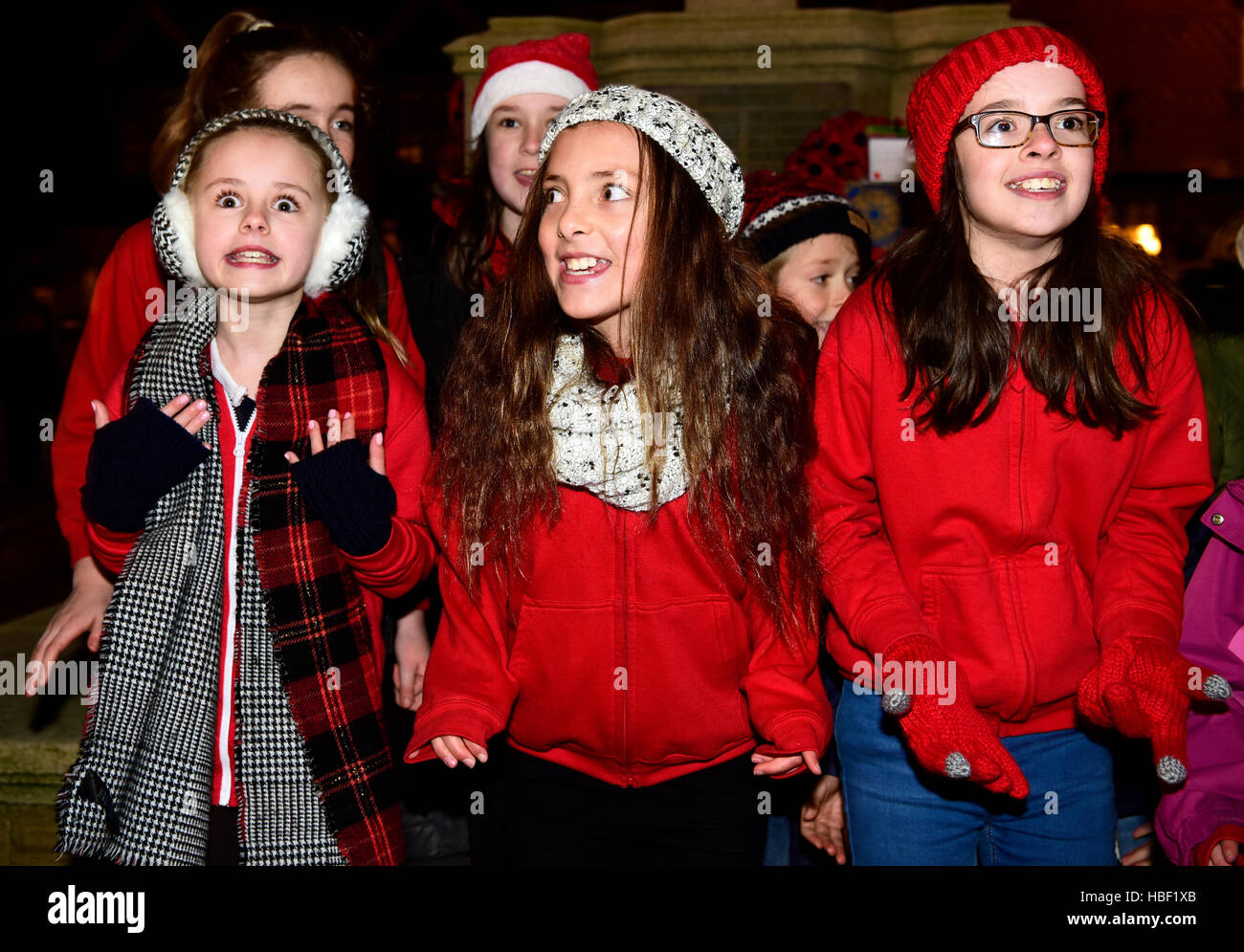 Giovani locali thespian gruppo che esegue in High Street a 2016 accensione della città le luci di Natale, Haslemere, Surrey, Regno Unito. Foto Stock