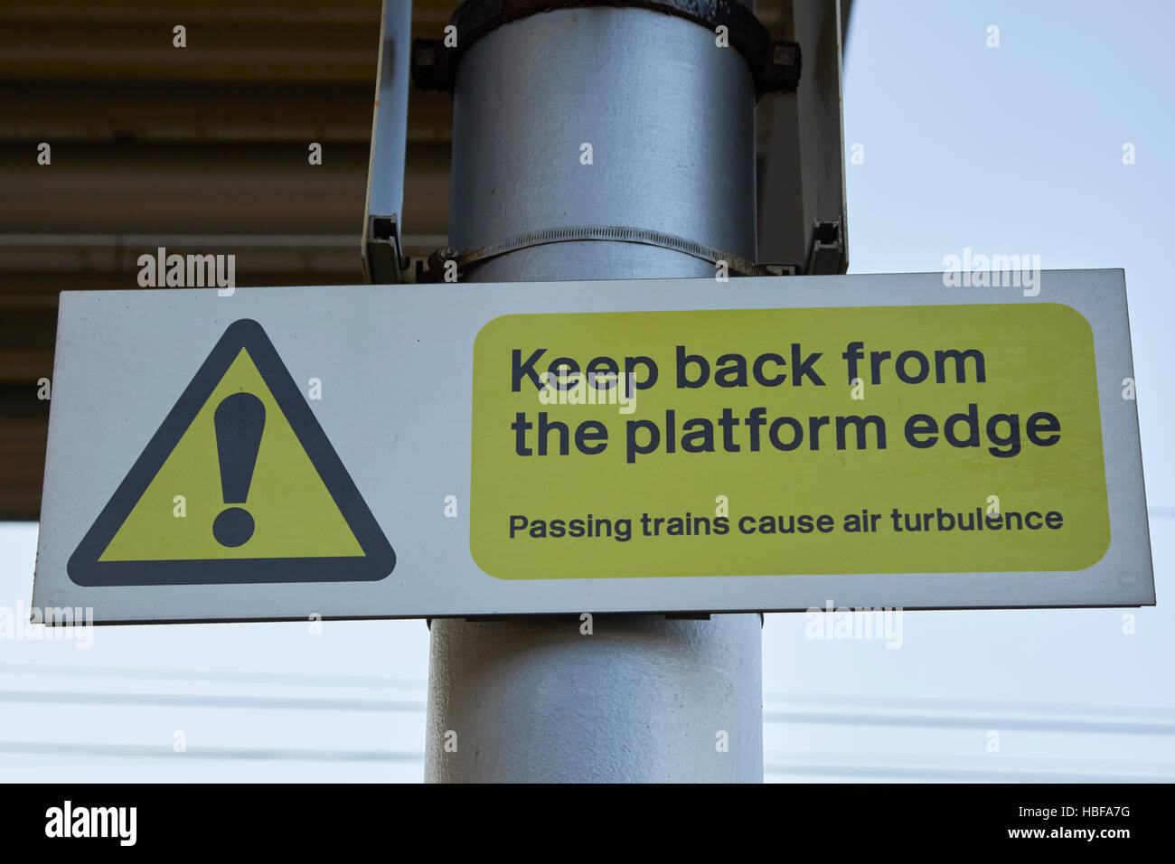 Stazione ferroviaria piattaforma segno di avvertimento tenere indietro dal bordo piattaforma passano i treni causare turbolenza di aria Foto Stock