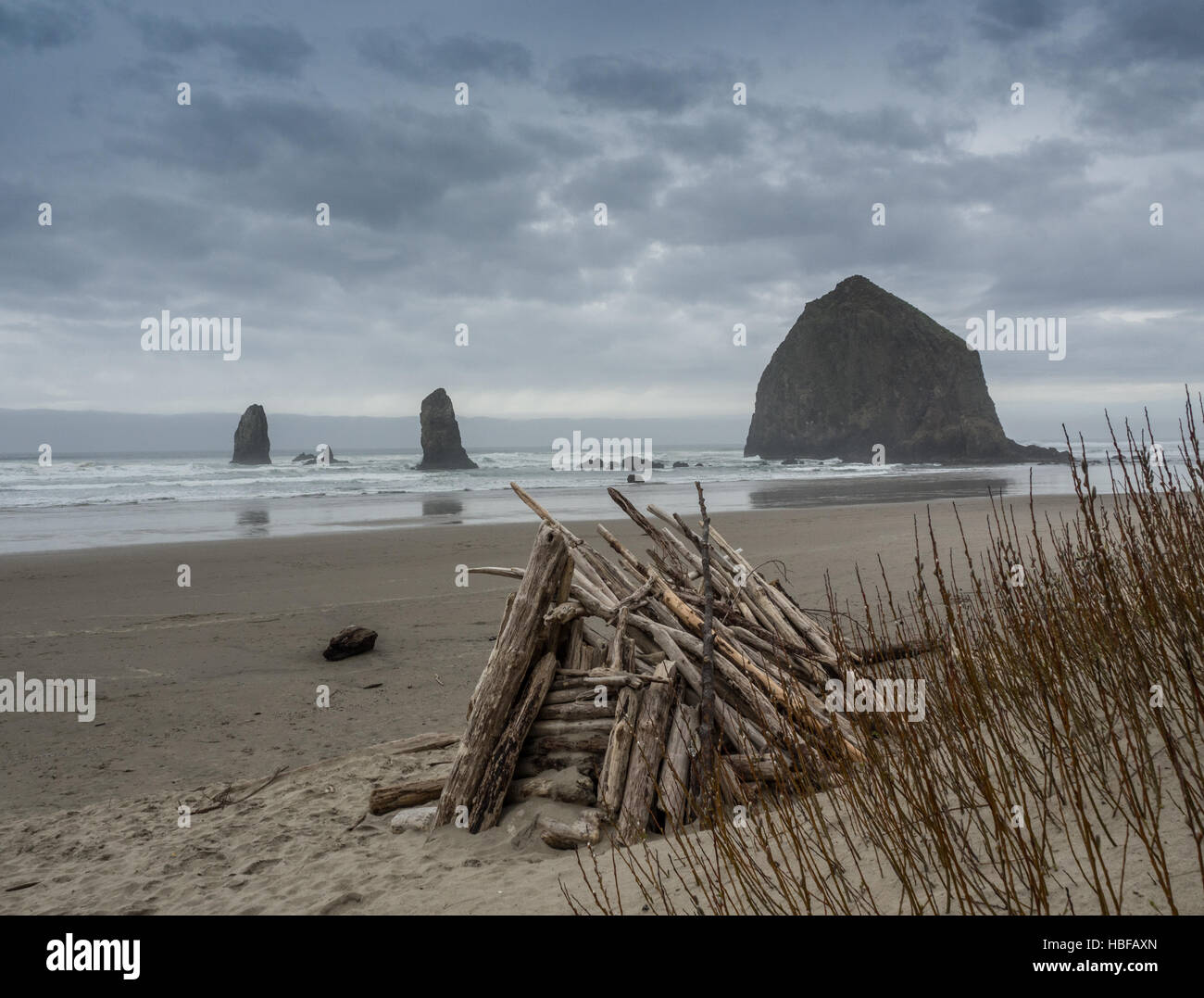 Un driftwood fort contro la spiaggia sullo sfondo di Cannon Beach Foto Stock