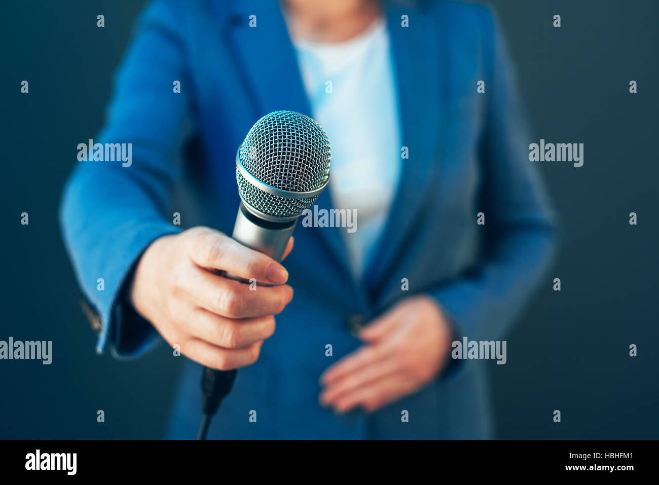 Elegante giornalista femmina la conduzione di affari intervista o conferenza stampa, mano con microfono Foto Stock