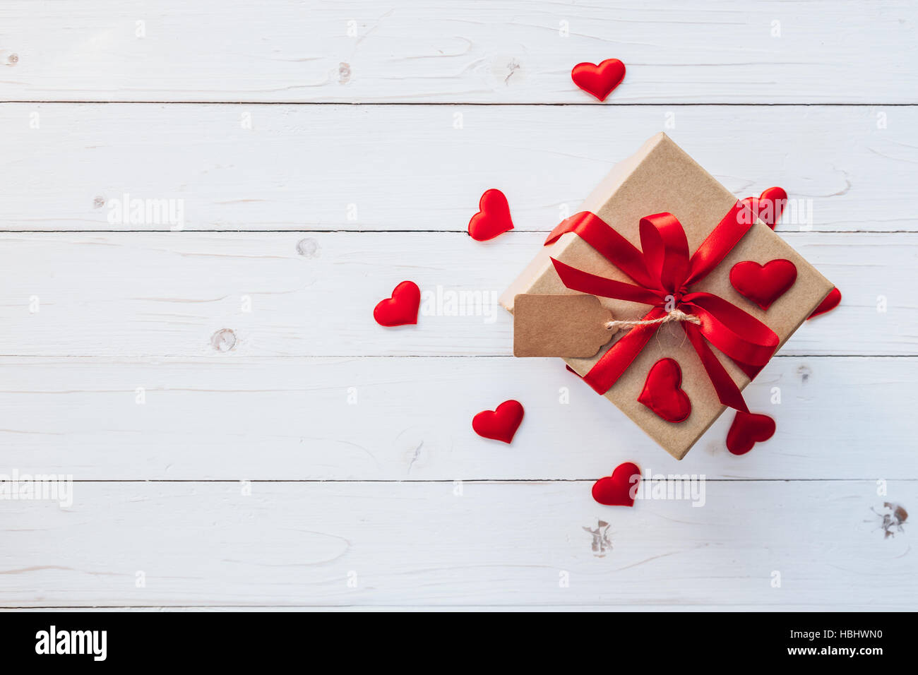 Vista superiore (sopra) confezione regalo e nastro rosso e cuore rosso per San Valentino sulla tavola di legno. Sfondo di San Valentino. Foto Stock