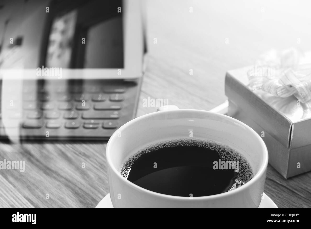 Tazza di caffè e il tavolo digitale dock tastiera intelligente,gold confezione regalo e legno tondo vassoio,matita colorata sul tavolo di legno,l'effetto filtro,bianco nero Foto Stock