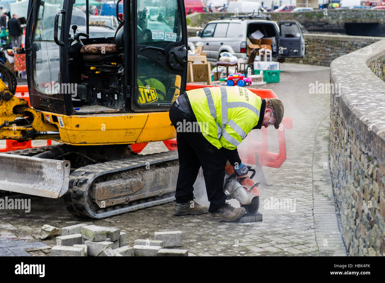 Il lavoratore del consiglio della contea di Cork taglia un mattone come parte di un lavoro di riparazione per la pavimentazione del mattone a Bantry, Cork occidentale, Irlanda. ©Andy Gibson. Foto Stock