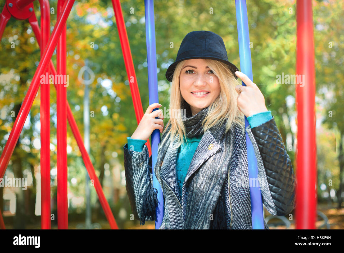 Giovane bella donna su un altalena nel parco, felice in una soleggiata giornata autunnale. Foto Stock