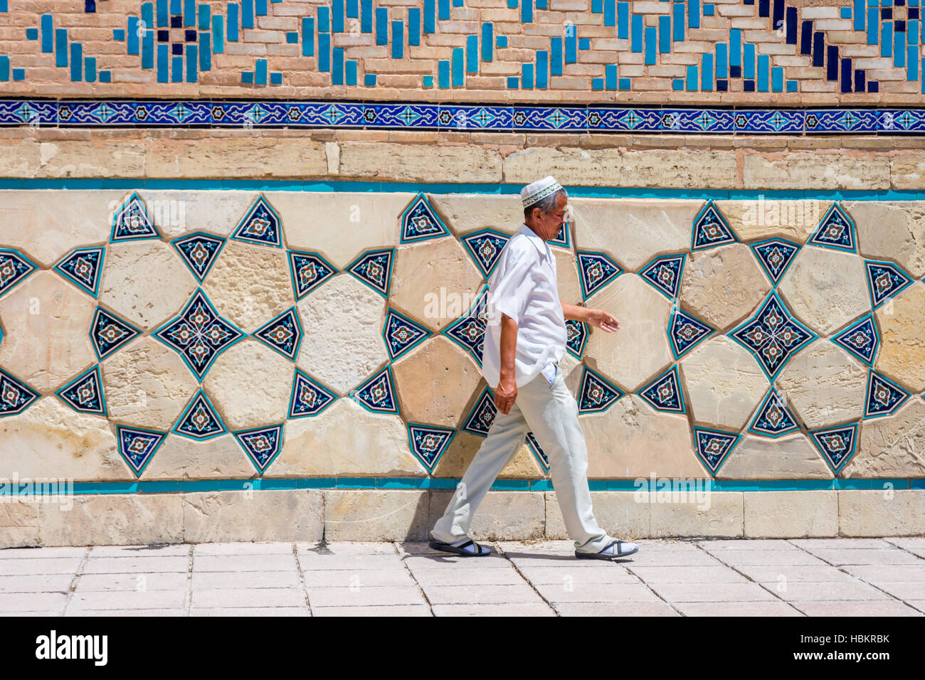 Turkestan, Kazakistan - 18 luglio: l uomo vecchio che passa parete con mosaico del mausoleo di Khoja Ahmed Yasawi. Luglio 2016 Foto Stock