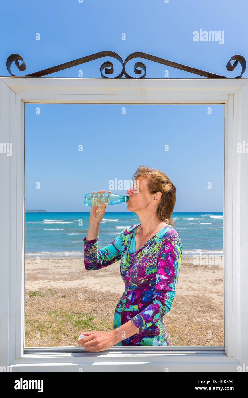 Bere donna nella finestra in mare Foto Stock