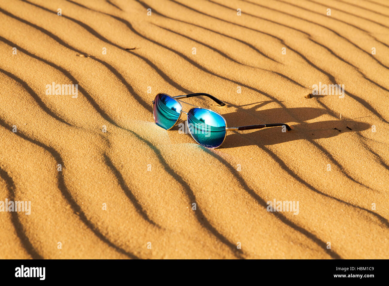 Occhiali da sole sulla sabbia , estate deserto è riflessa nei bicchieri. Foto Stock