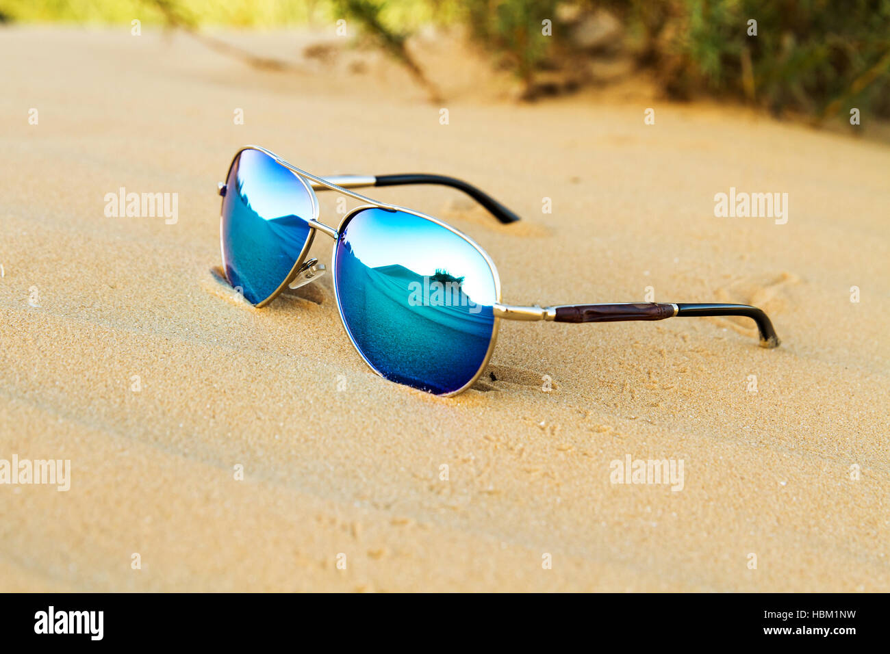 Occhiali da sole sulla sabbia , estate deserto è riflessa nei bicchieri. Foto Stock