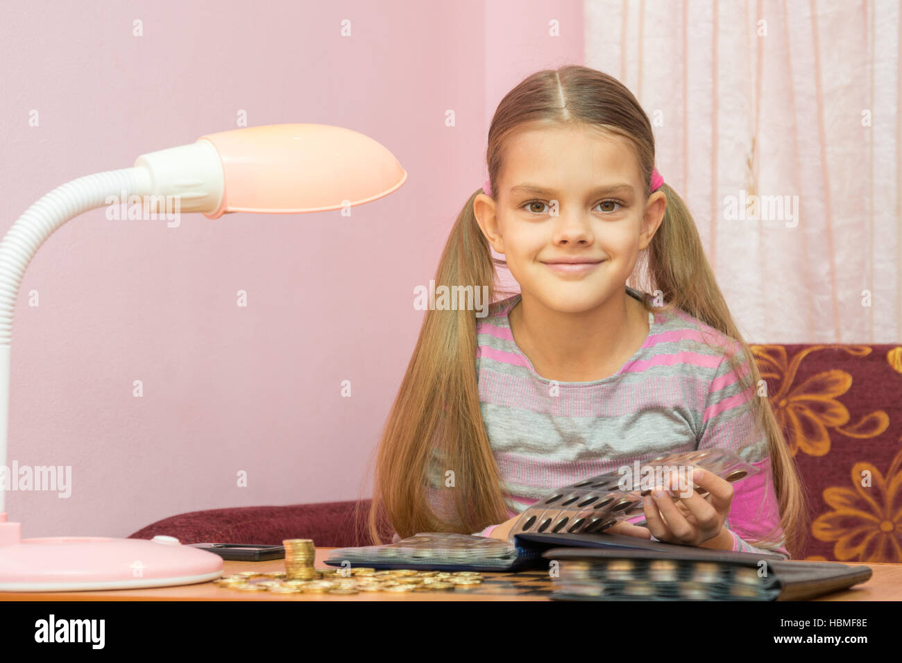 Il bambino a sfogliare un album per collezionisti di monete e guardato dentro il telaio Foto Stock