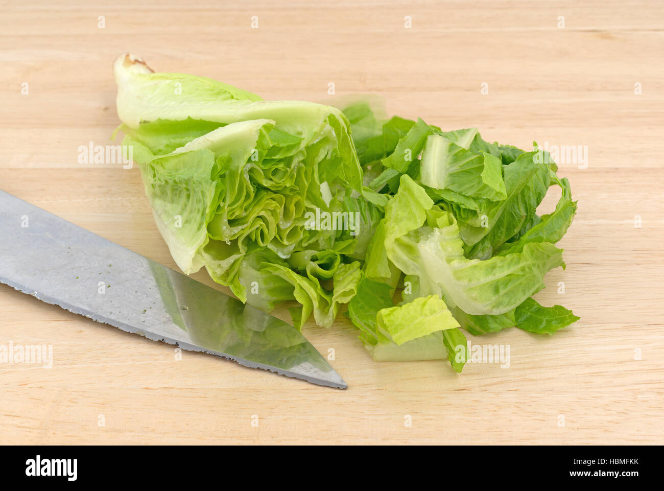 Lattuga romana che è stato affettato su un legno tagliere con un coltello a lato. Foto Stock