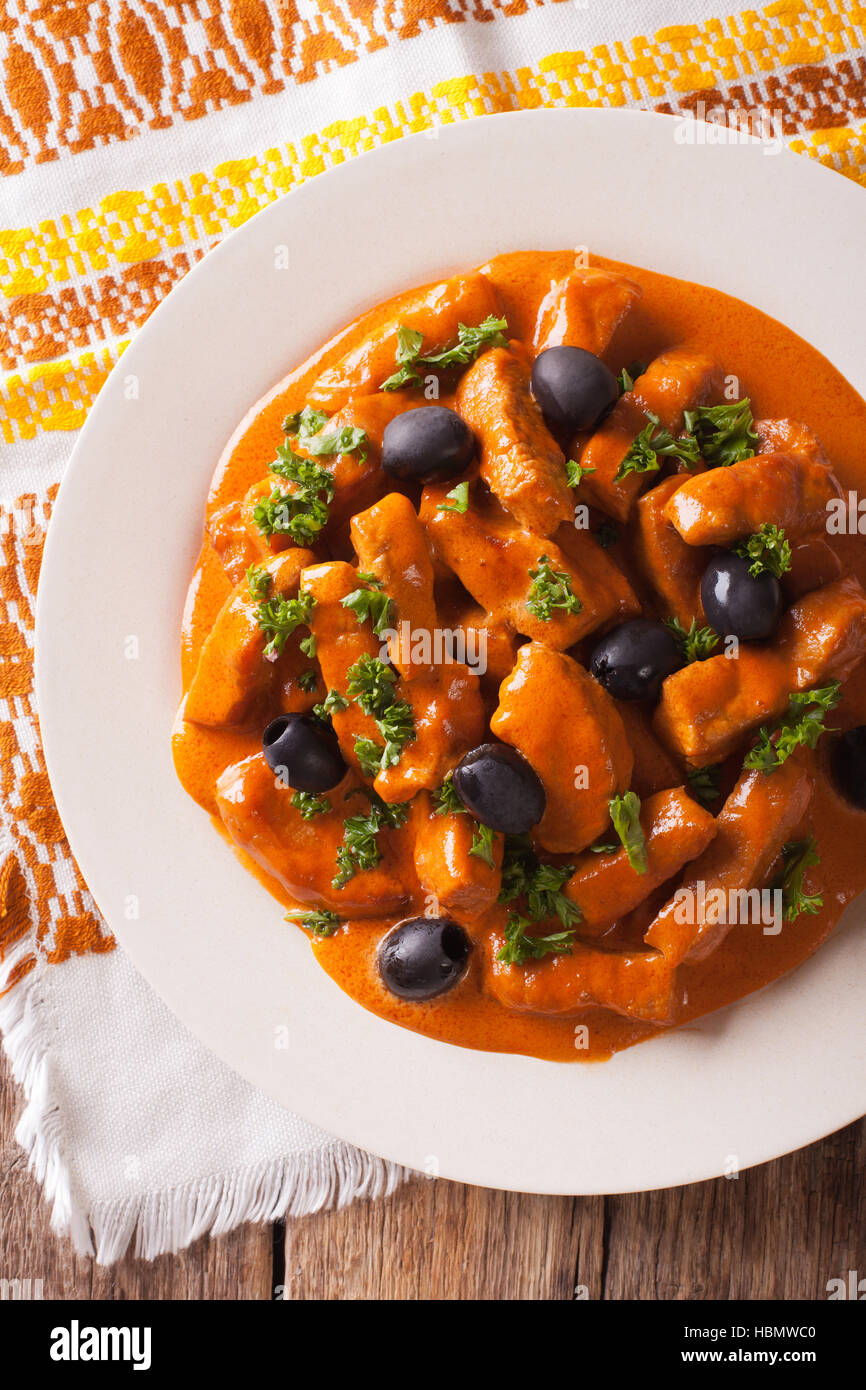 La cucina spagnola: Raxo di maiale in salsa piccante con olive close-up su una piastra. vista verticale da sopra Foto Stock