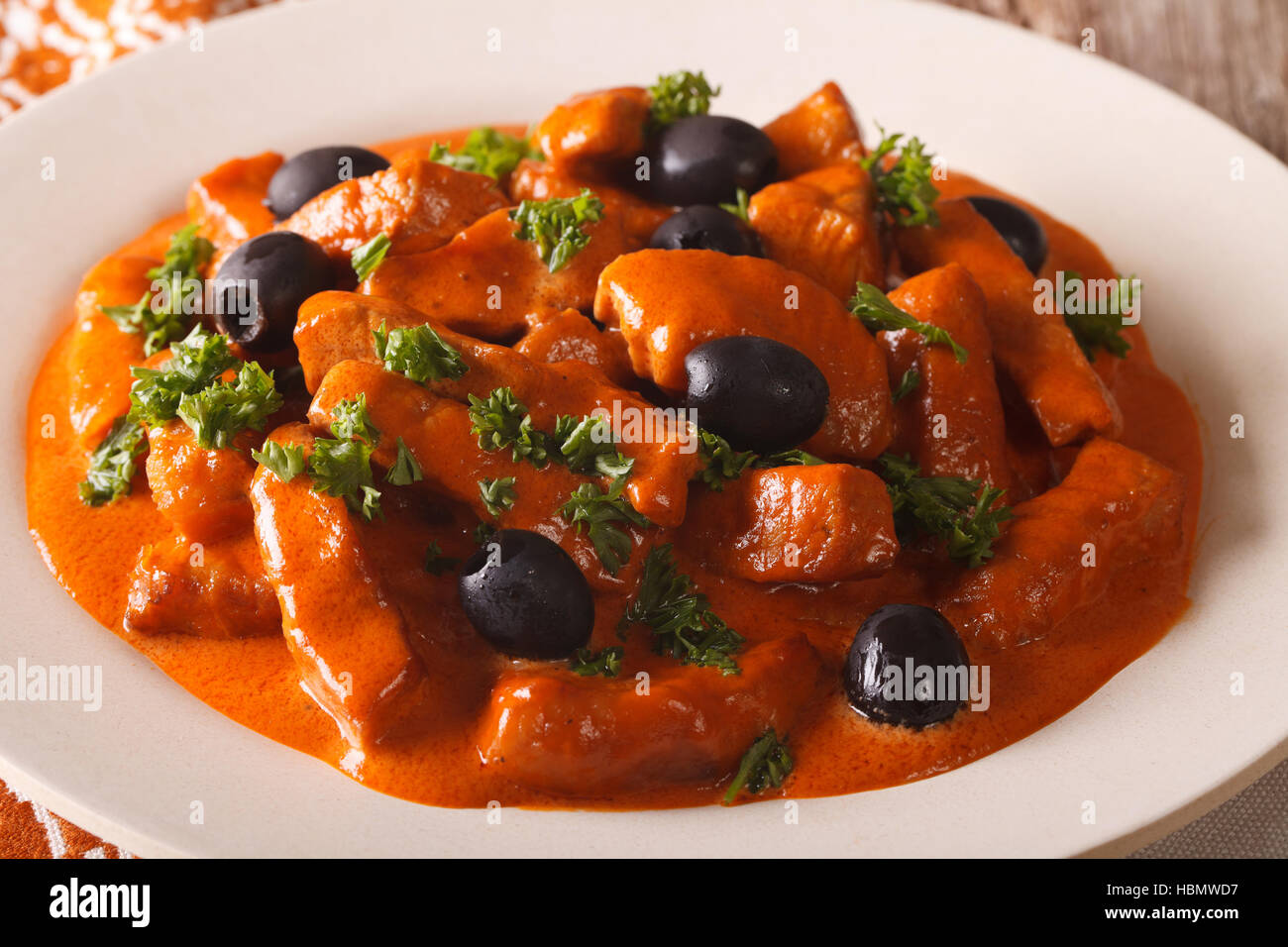 La cucina spagnola: Raxo di maiale in salsa piccante con olive close-up su una piastra orizzontale. Foto Stock