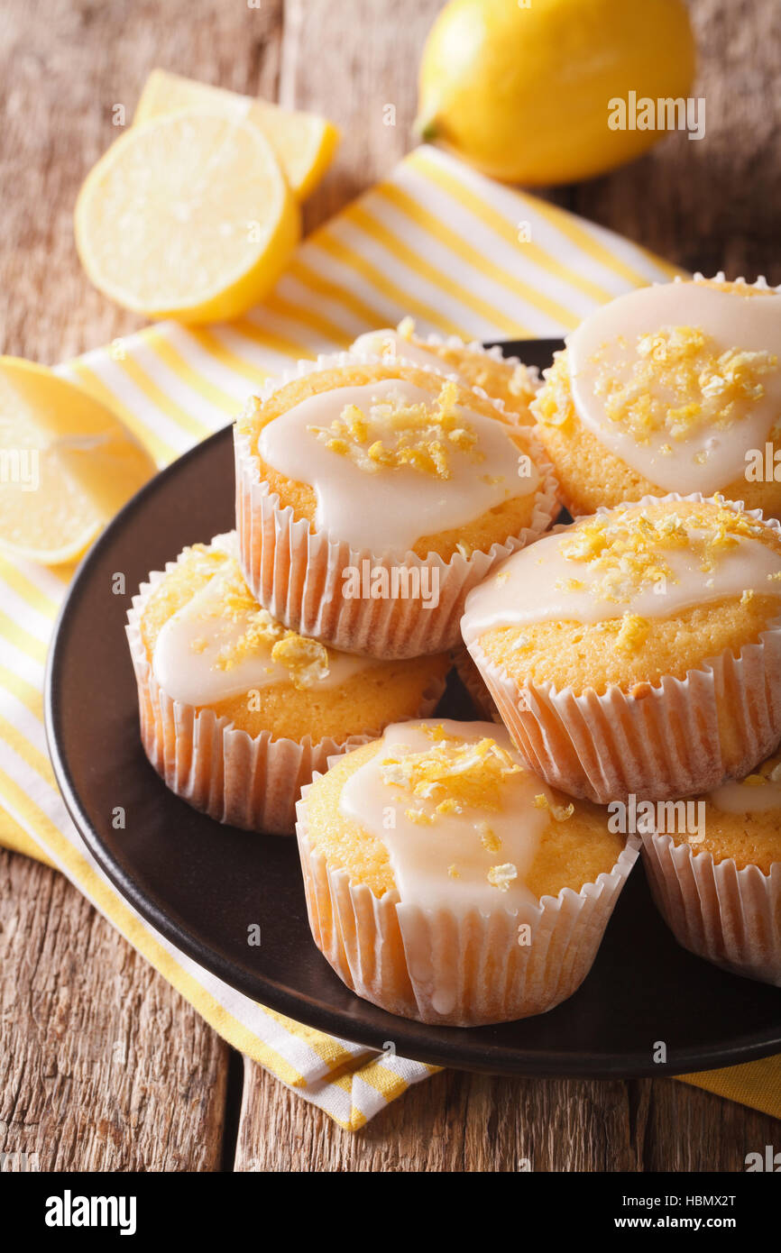 Dolce limone muffin con la scorza e zucchero a velo close-up su una piastra sul piano verticale. Foto Stock