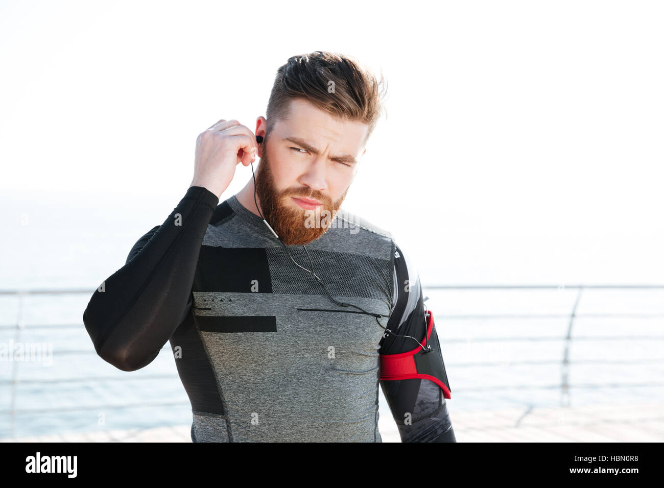 Close up runner in cuffie in prossimità del mare. Guardando lontano Foto Stock