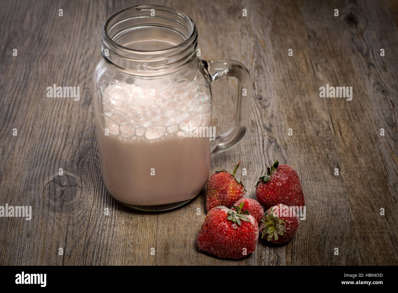 Agitare il latte con proteine di fragola in un vasetto di marmellata. Foto Stock