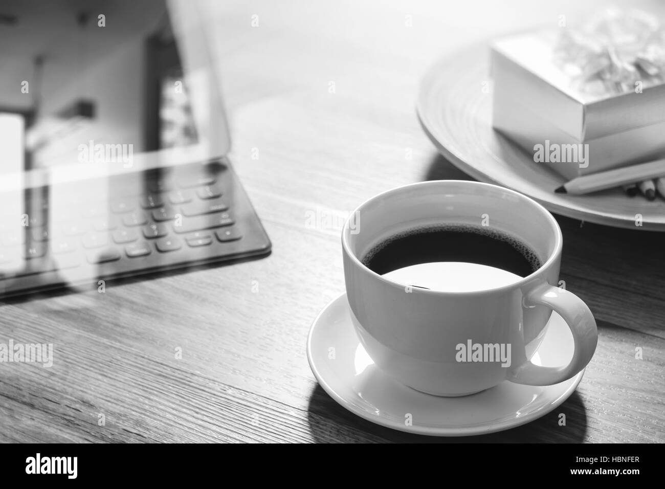 Tazza di caffè e il tavolo digitale dock tastiera intelligente,gold confezione regalo e legno tondo vassoio,matita colorata sul tavolo di legno,l'effetto filtro,bianco nero Foto Stock