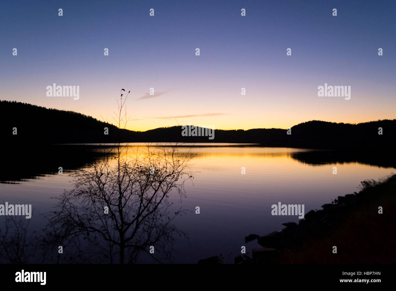 Tramonto sul lago Ladoga. Le ombre degli alberi si riflette nell'acqua. Tramonto crea un alone che circonda queste ombre. Foto Stock