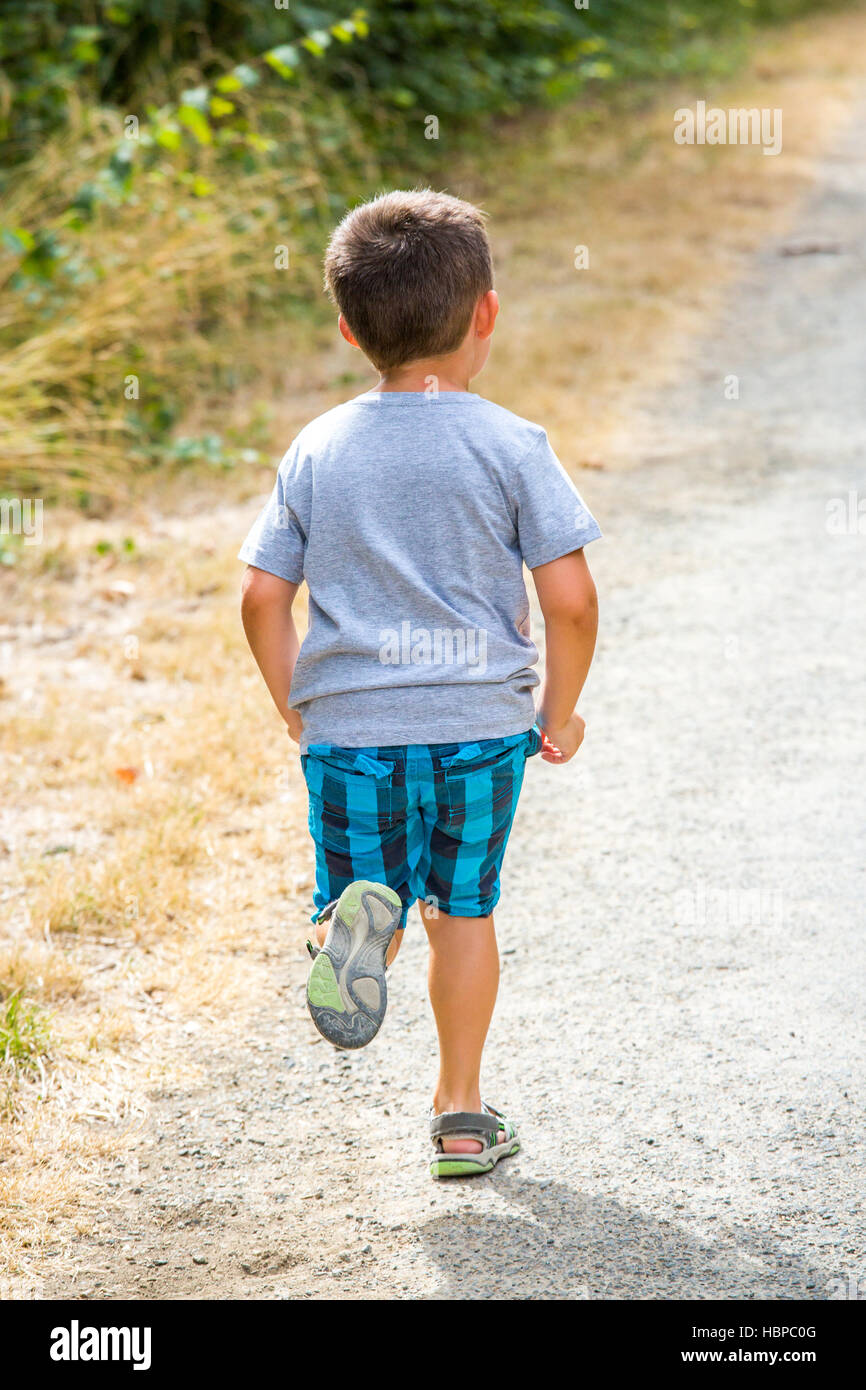 Bambino che corre lungo una strada di campagna Foto Stock