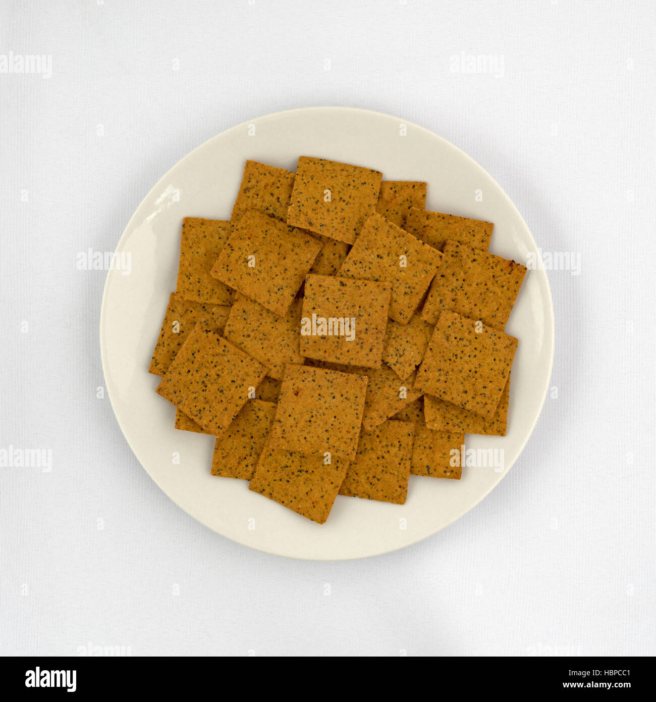 Vista dall'alto di gourmet teff grano intero snack crackers su una piastra sulla cima di una tovaglia bianca. Foto Stock