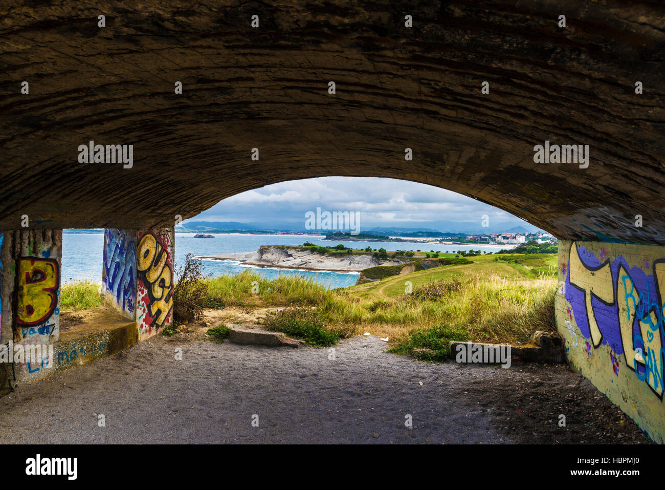 Bunker con graffiti sul punto di vista del Cabo Mayor. Costa rocciosa lungo le scogliere con persone che passeggiano a Santander, Cantabria, SPAGNA Foto Stock