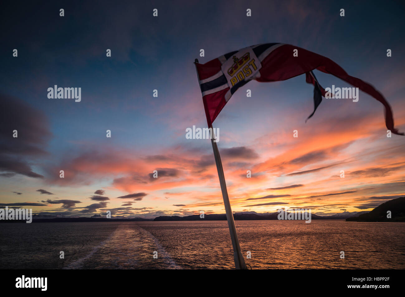 Norwegian bandiera nazionale con inserto Post battenti dalla poppa di Hurtigruten MS Polarlys, Norvegia. Foto Stock