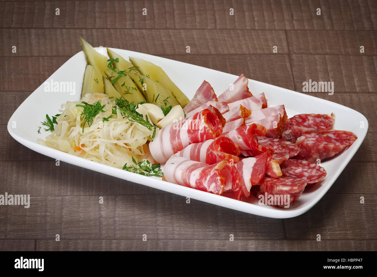 Fette di pancetta, prosciutto e salsicce con cetriolo sottaceto, cavolo e aglio. Foto Stock