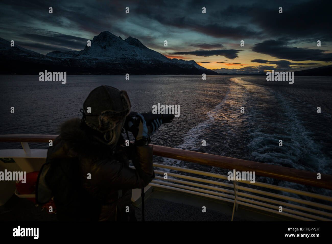 Una femmina matura cattura un'immagine mentre sulla Hurtigruten al tramonto, Norvegia. Foto Stock