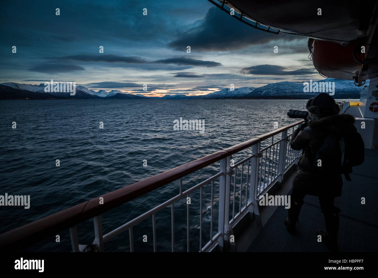 Una femmina matura cattura un'immagine mentre sulla Hurtigruten al tramonto, Norvegia. Foto Stock