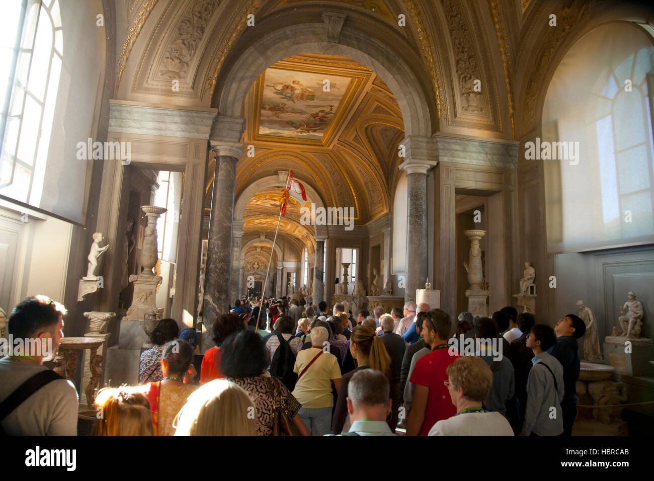 Roma, Musei Vaticani, scultura romana gallery interior con guida del gruppo che porta bandiera e schiere di turisti Foto Stock