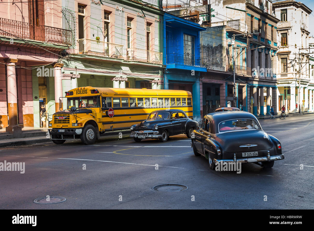 Un paio di vecchio nero timer catturato al fianco di un vecchio giallo scuola bus una mattina su una strada larga in Centro di Havana. Foto Stock