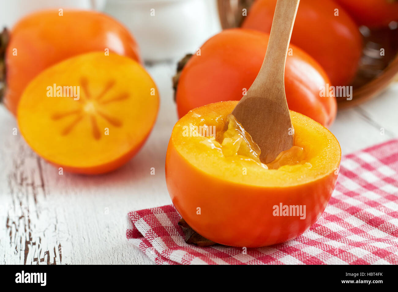 Kaki (Diospyros kaki) su bianco rustico sfondo di legno Foto Stock