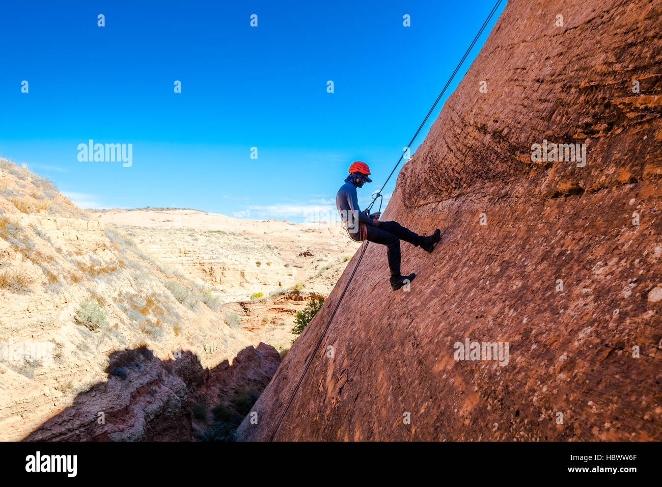 Un giovane uomo practice rappelling durante la ricezione di una sosta vigili del fuoco dal di sotto Foto Stock